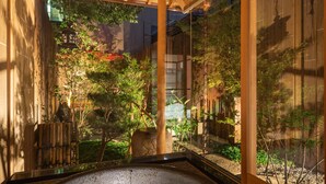 A stone hot tub in a wooden room with large windows overlooking a garden. - KumoMachiya Takoyakushi (Kyoto)