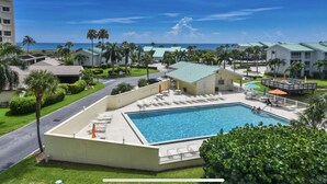 Ett semesterhotell med en swimmingpool, solstolar och utsikt över havet.