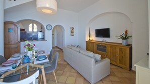 A modern living room with a sofa, dining table, and kitchen area. - Casa Malu' (Praiano)