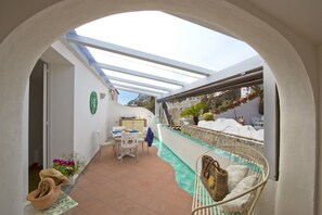 A covered patio with a pool, outdoor seating, and a view of a hillside. - Casa Malu' (Praiano)