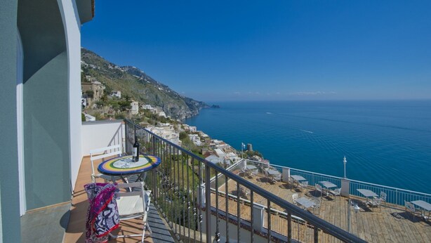 A balcony with a view of the sea, a table with chairs, and a patterned cloth. - Casa Malu' (Praiano)