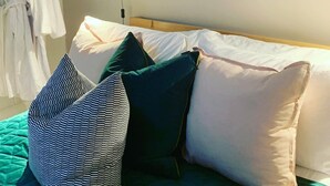 A bedroom with a bed, pillows, a hanging robe rack, a wall-mounted lamp, and a round mirror reflecting a brick wall. - Boutique garden apartment with decking and views (Ludlow)