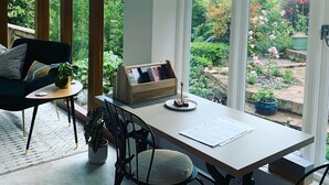 A modern dining area with a wooden table, chairs, and a view of a garden through large windows. - Boutique garden apartment with decking and views (Ludlow)