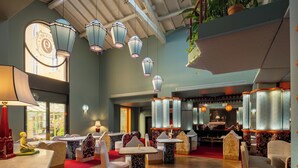 Un restaurant doté de nombreuses tables et chaises, de lanternes suspendues et d’un tapis rouge.