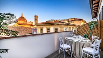 A rooftop terrace with a table set for dining, overlooking a historic building with a dome and tower.