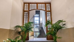 Un escalier menant à un deuxième étage, bordé de plantes en pot et d’une porte en bois.