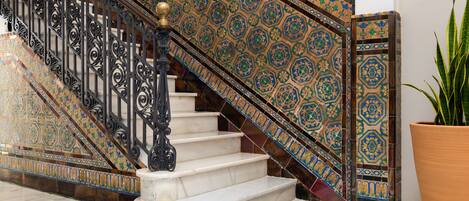 A staircase with ornate metal railings and patterned tile walls.