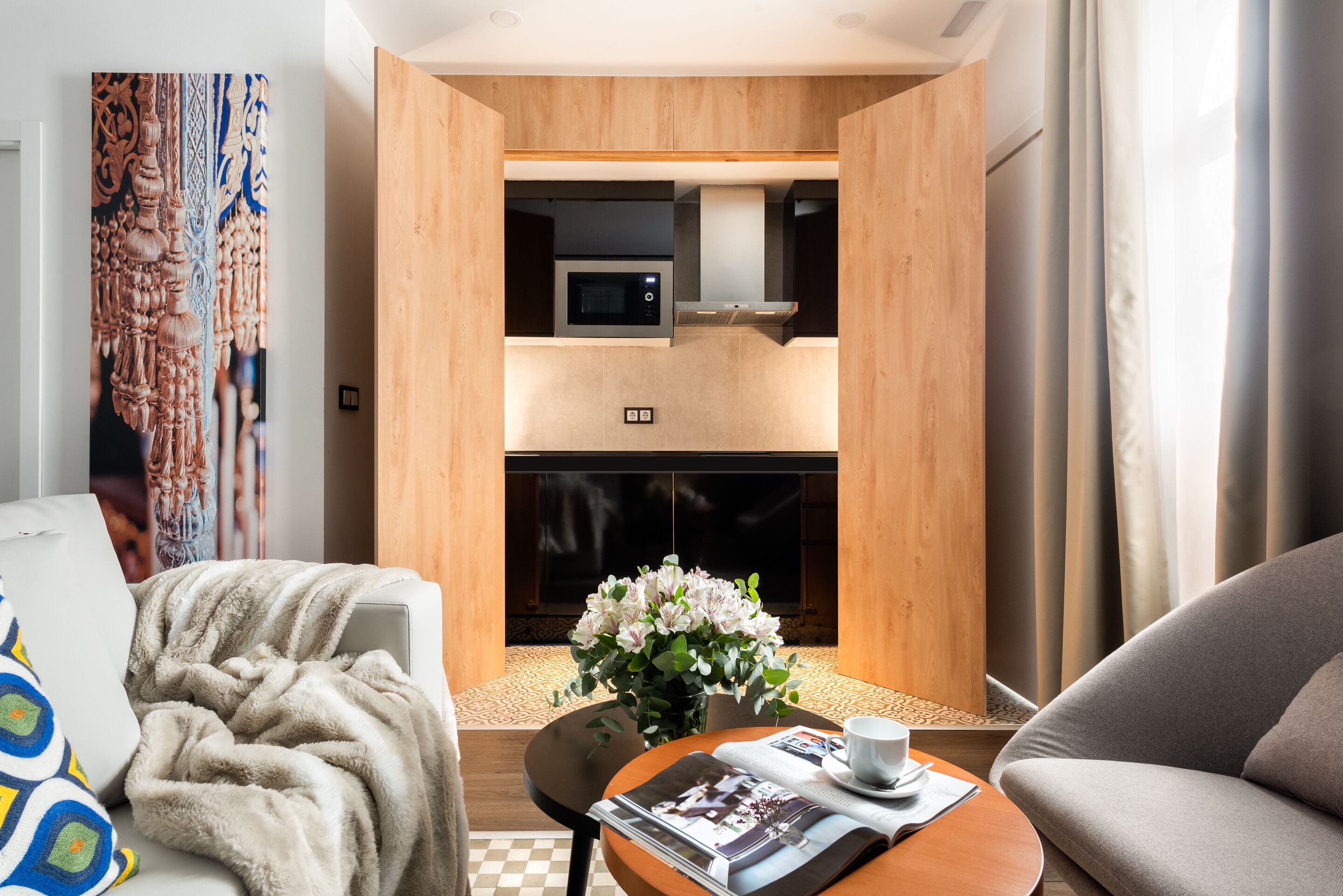 A cozy hotel room with a sofa, a small table with a magazine, a vase of flowers, and a fireplace.