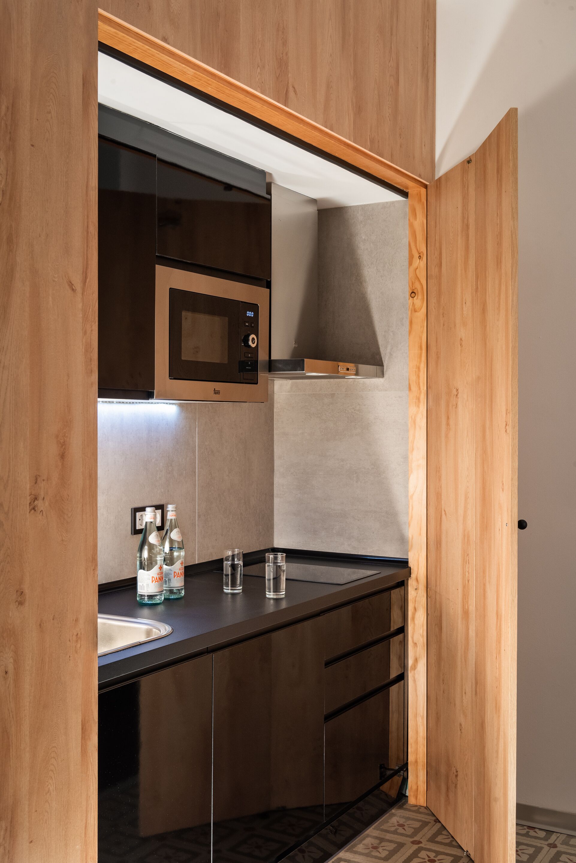 A modern kitchen with wooden cabinetry, a built-in microwave, and a stainless steel sink.
