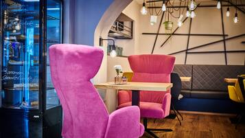 A modern interior with pink chairs, a wooden table, and a glass display case.