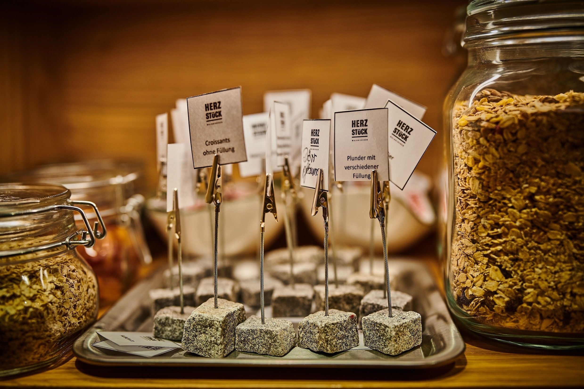 A display of various types of granola with labels indicating different flavors and fillings.