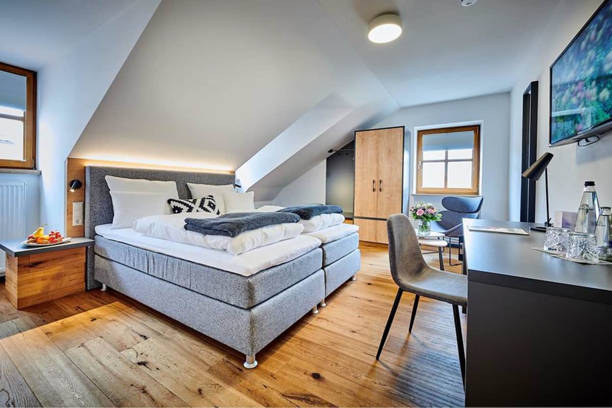 Un dormitorio moderno con cama elevable, suelo de madera, un escritorio y un ventanal grande.