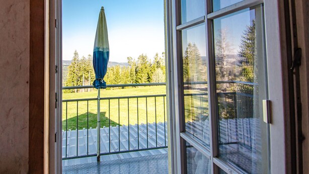 A view from a balcony with a metal railing, a clear sky, and a distant landscape with trees and mountains. - Gasthaus Deutscher Jäger (Hornberg)