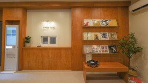 A reception desk with a wooden panel design, a digital kiosk, and a small plant. - La Villa Foret (Busan)