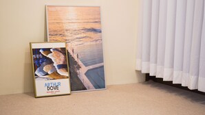 A framed artwork titled 'Arthur Dove' depicting a beach scene, placed on a carpeted floor next to a white curtain. - La Villa Foret (Busan)