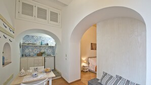 A compact living space with a kitchenette, a dining area, and a seating area with a sofa. - Suite Malu' (Praiano)