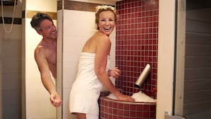 Un baño con zona de ducha y pared con azulejos rojos.