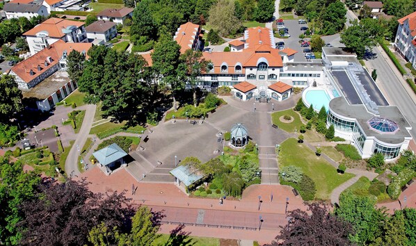 An aerial view of a residential area with a central courtyard, surrounded by houses with red-tiled roofs, and a large building with a dome structure.