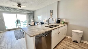 A modern kitchen with a dishwasher, double sink, and a coffee maker. - Royal Palms 402 1 Bedroom Condo by RedAwning (Gulf Shores)