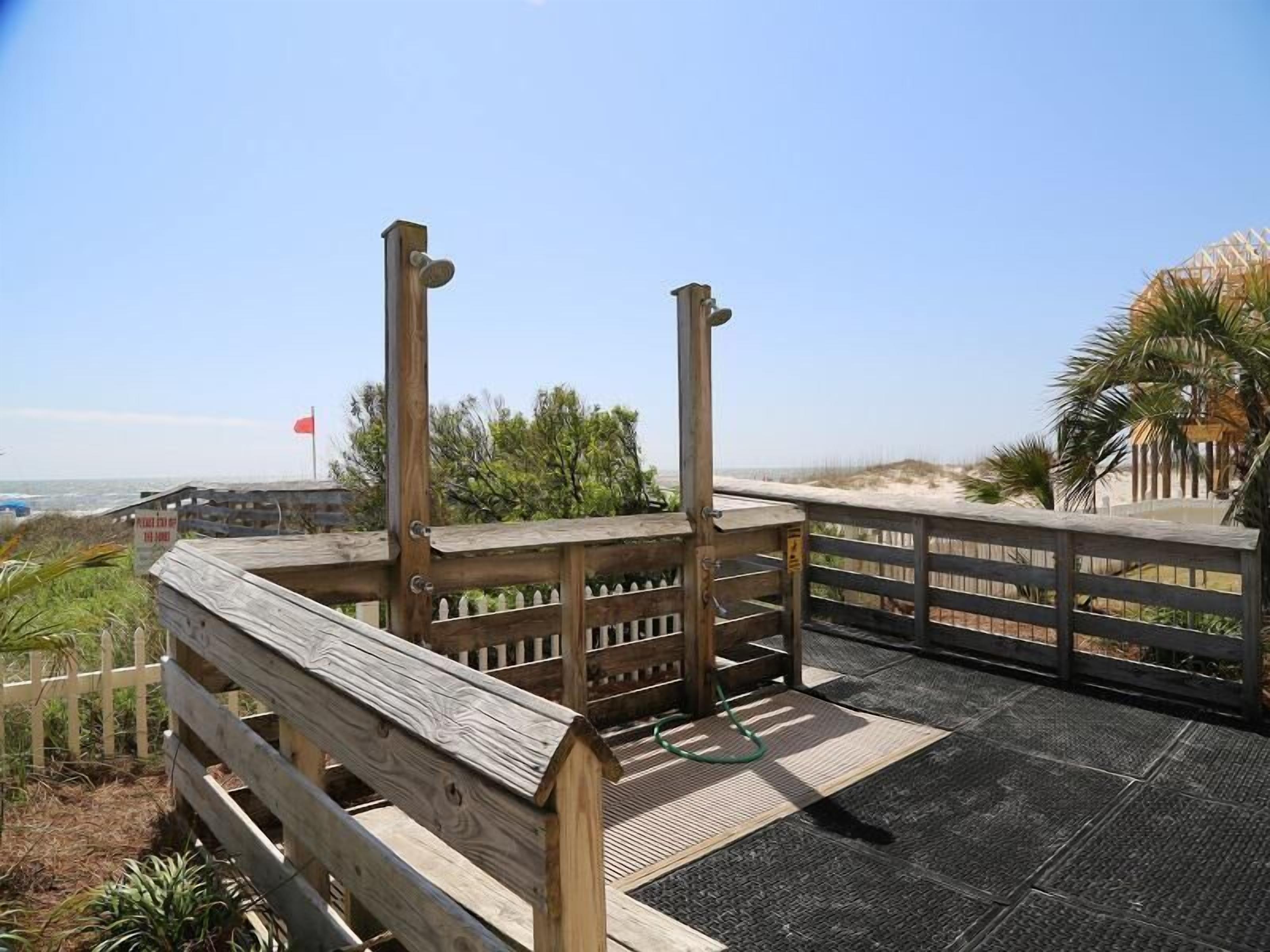 A wooden observation deck with a metal railing, overlooking a beach and ocean.