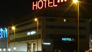 A hotel with a prominent "HOTEL" sign, multiple floors, and a parking lot. - Spa Suites Odeon (Naron)