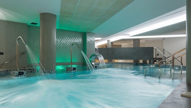 An indoor swimming pool with multiple water slides and a modern design. - Spa Suites Odeon (Naron)