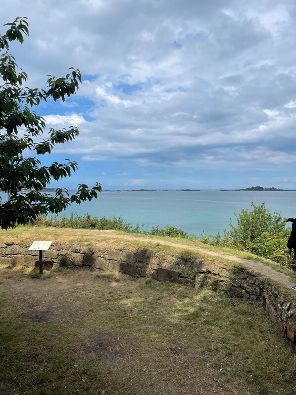 A coastal view with a grassy area, a stone wall, and a sign. - Pen Ty, a cozy little fisherman's cottage in Paimpol, right on the waterfront. (Paimpol)