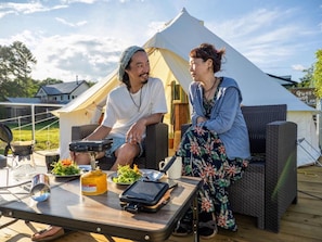 Two people sitting on wicker furniture outdoors with a tent in the background. - Guesthouse leaf (Hokuto)