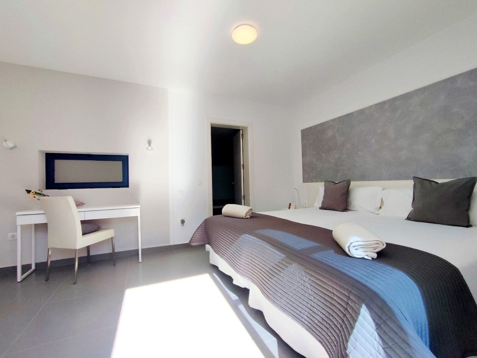 Een moderne hotelkamer met een groot bed, een bureau en een stoel.