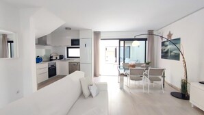 A modern apartment with a living room, dining area, and kitchen. - FuerteVillage (Pajara)