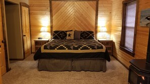 Um quarto aconchegante com uma cama grande, duas luminárias de cabeceira, um painel de madeira e uma janela com persianas.