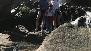 A family standing on rocks in front of a waterfall.