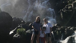 A waterfall with a rocky foreground and a clear sky.