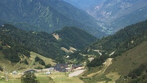 A mountainous landscape with a valley, a small settlement with buildings, and a distant mountain peak.