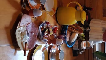 A dining table with various dishes, cups, and a yellow kettle.