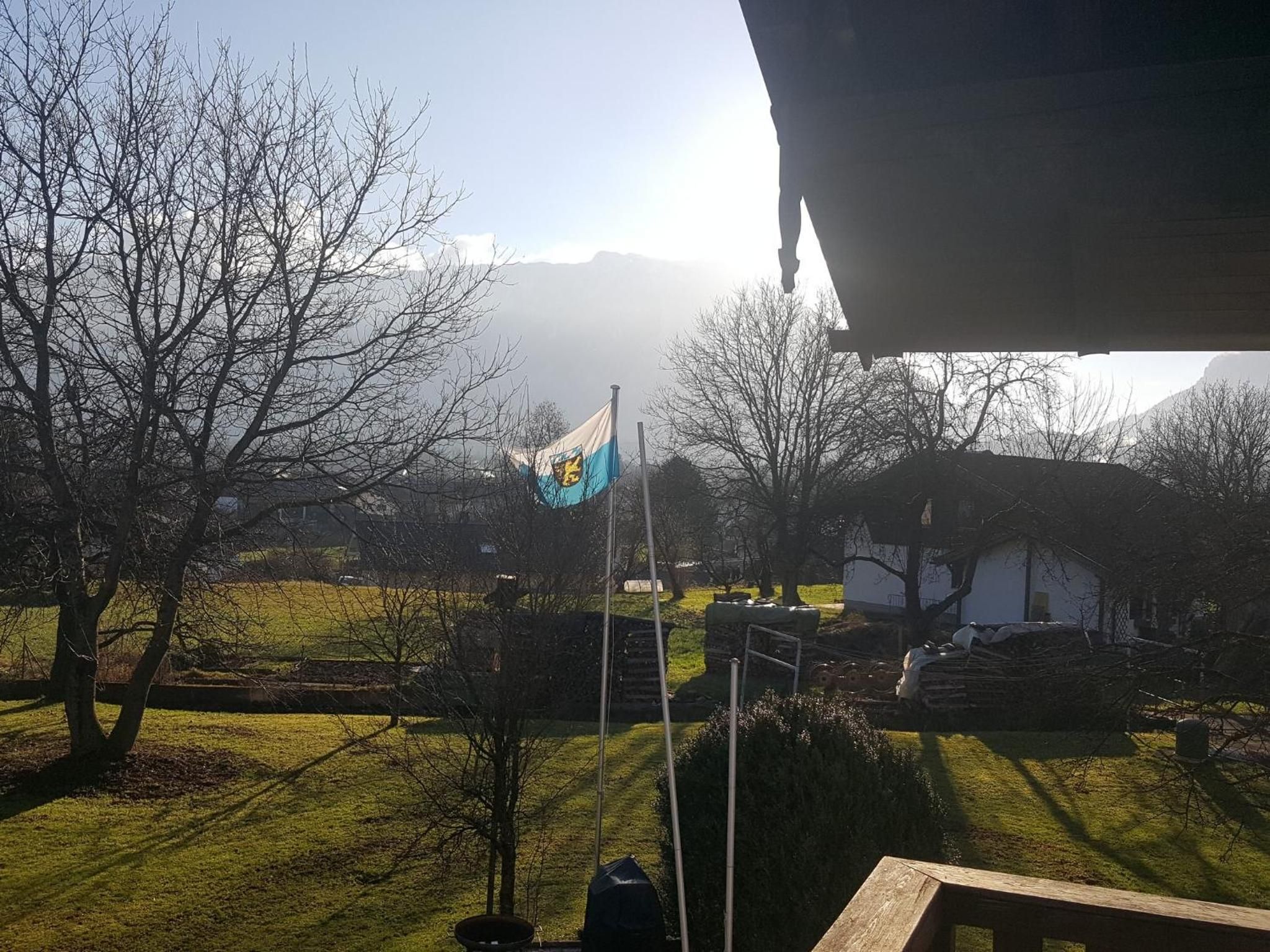 A flagpole with a flag, a grassy area, and a building in the background.