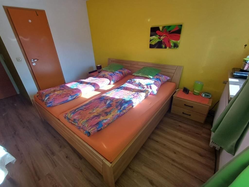 A bedroom with a wooden bed, two pillows, a nightstand, and a green towel.
