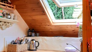 Eine kleine Küche mit Oberlicht, Holzschränken, einer Mikrowelle und einer Kaffeemaschine.