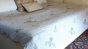 Ein Schlafzimmer mit Bett, einer Kronleuchter, Holzbalkendecke und einer Wand mit dekorativem Herz-Wimpel.