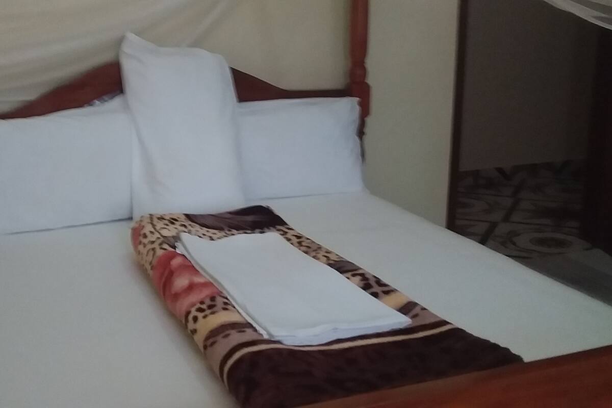 A bed with a white sheet, a leopard print blanket, and a white pillow.