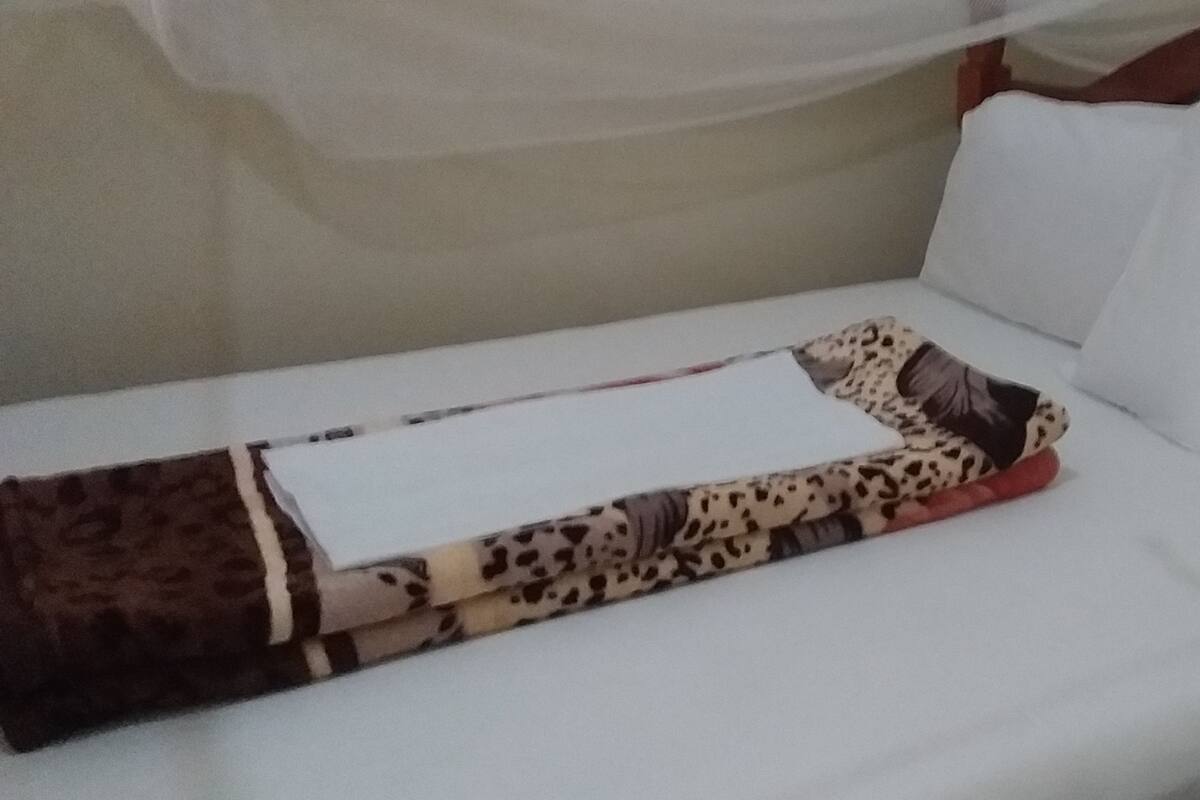 A single bed with a white mattress and a patterned blanket.
