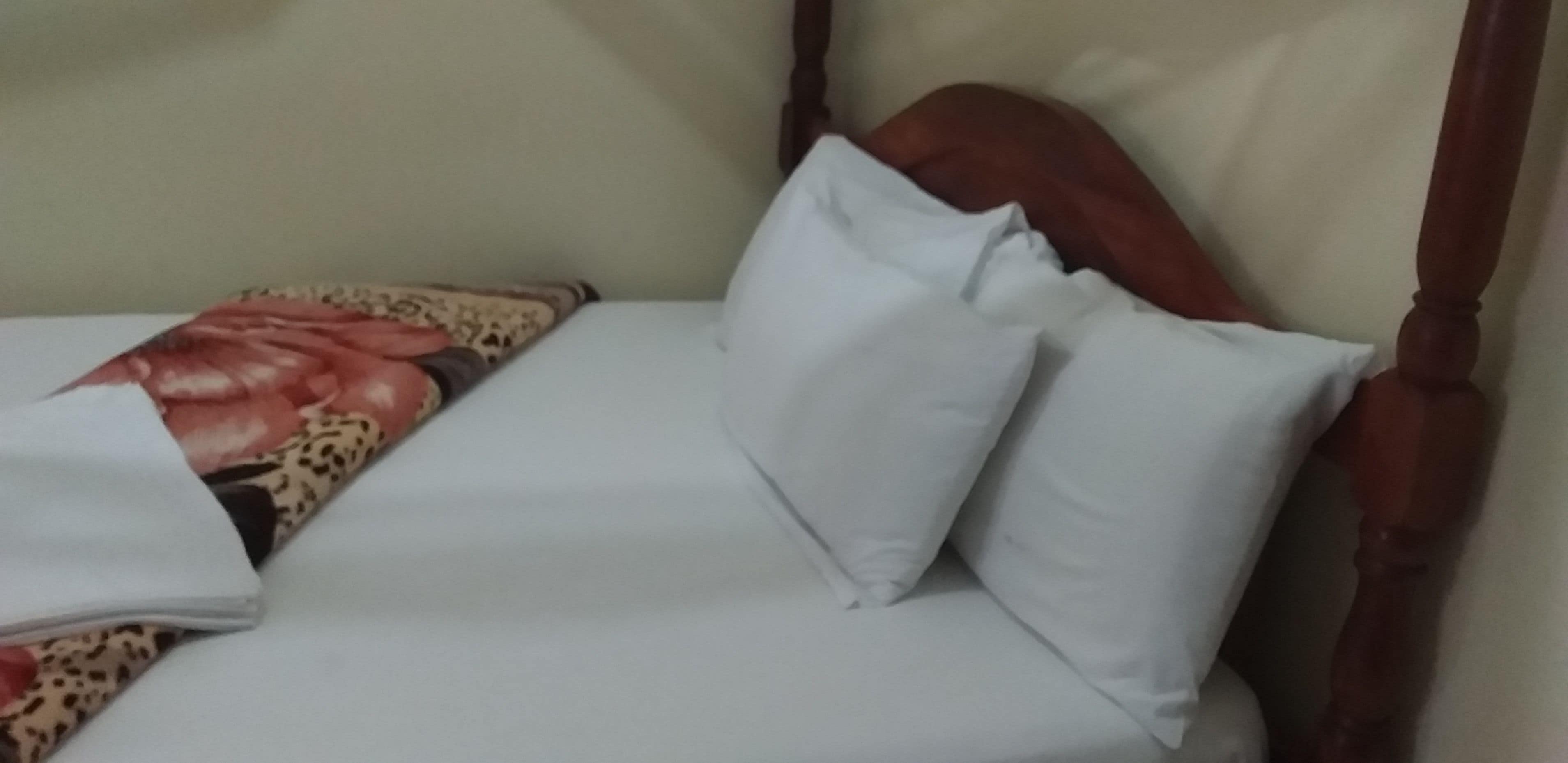 A bed with a wooden headboard, white bedding, and a floral-patterned blanket.