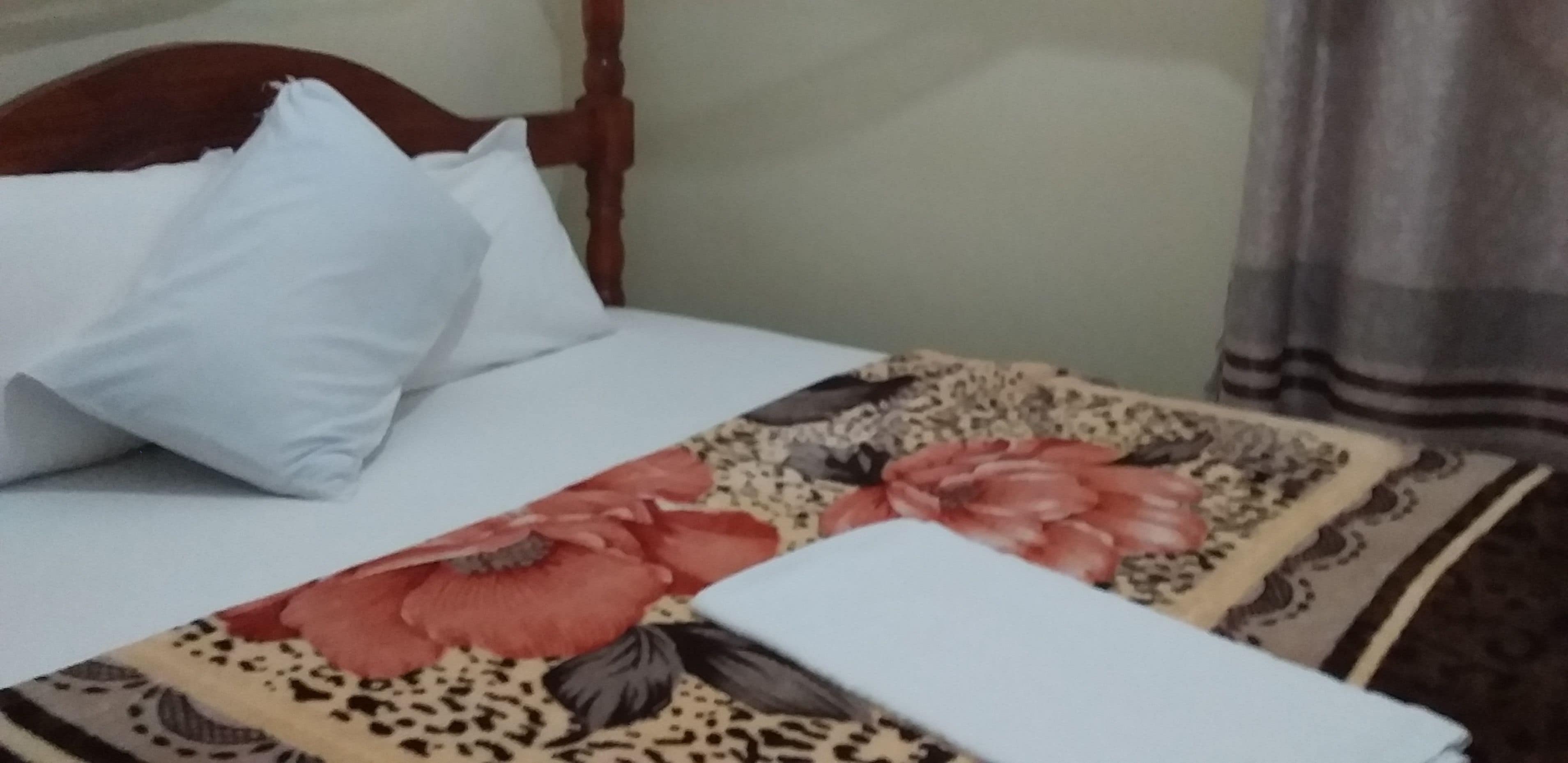 A bed with a floral bedspread, white pillows, and a wooden headboard.