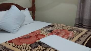 A bed with a floral bedspread, white pillows, and a wooden headboard.