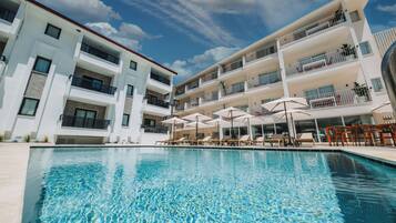 Una piscina al aire libre de temporada, sombrillas, tumbonas