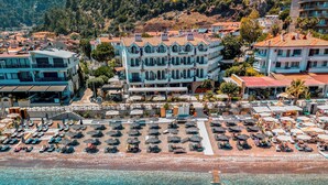 A coastal hotel with a beachside terrace, clear blue waters, and a mountainous backdrop. - Diplomat Hotel (Marmaris)
