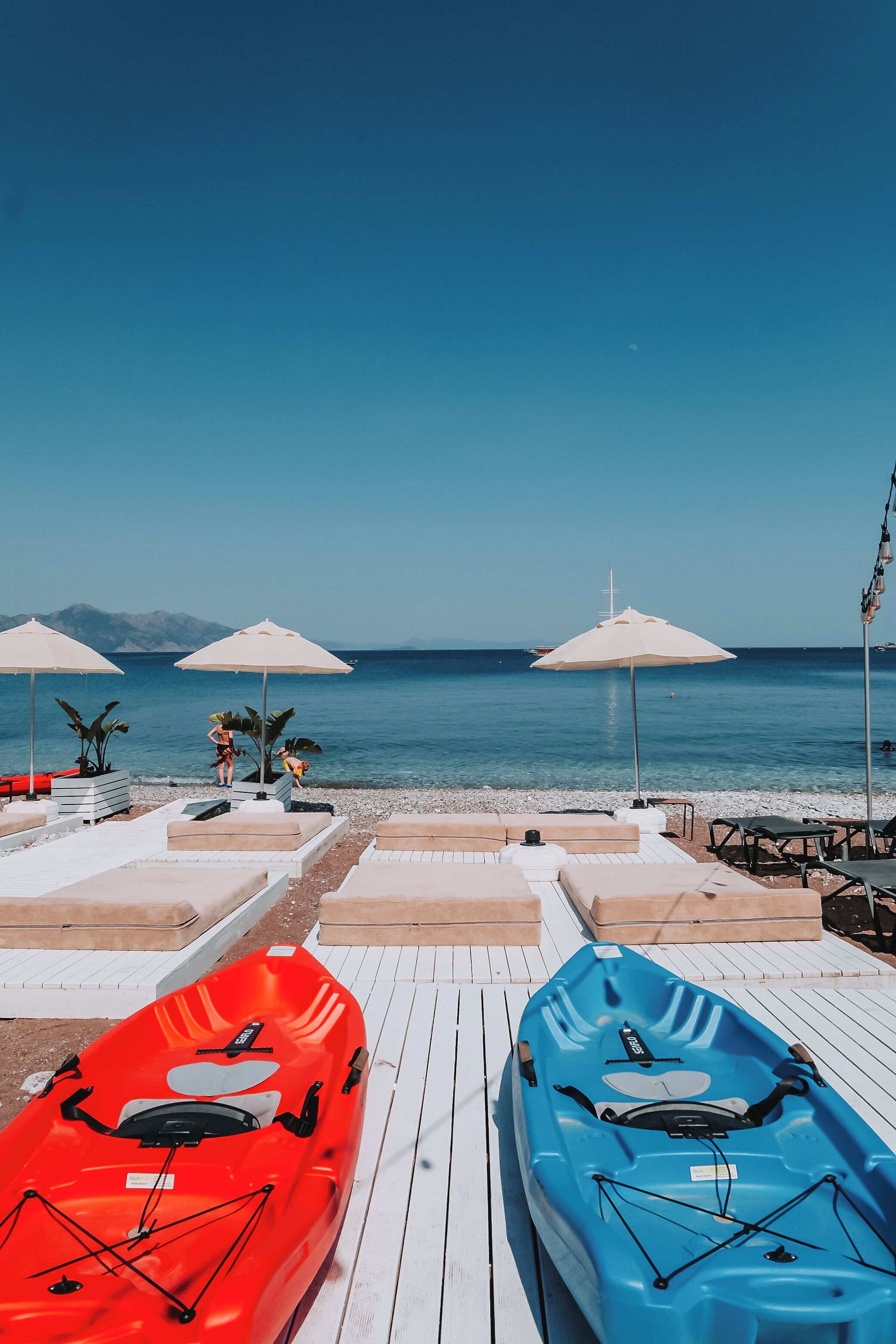 Une plage avec des kayaks, des parasols et des chaises longues.