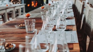 A long dining table set with wine glasses and water glasses, with a fireplace in the background. - Diplomat Hotel (Marmaris)