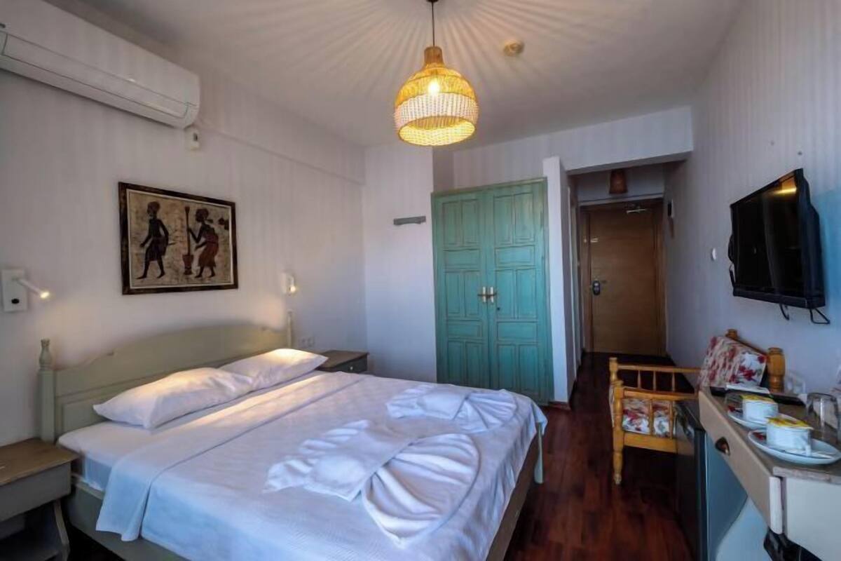 Une chambre à coucher avec un lit, un bureau avec une chaise, une télévision et une porte.