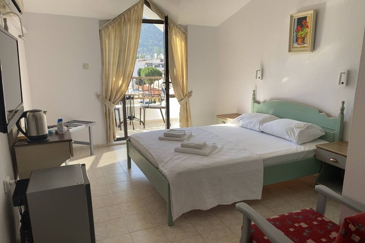 Une chambre d’hôtel avec un lit, un bureau, une chaise et une vue sur l’extérieur.